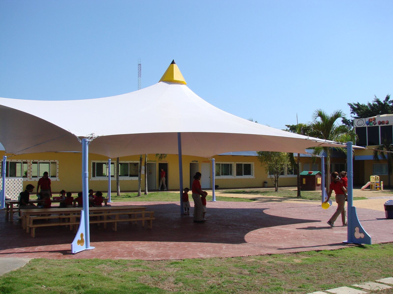 Cubierta tensada con punta en forma de lápiz en patio de colegio