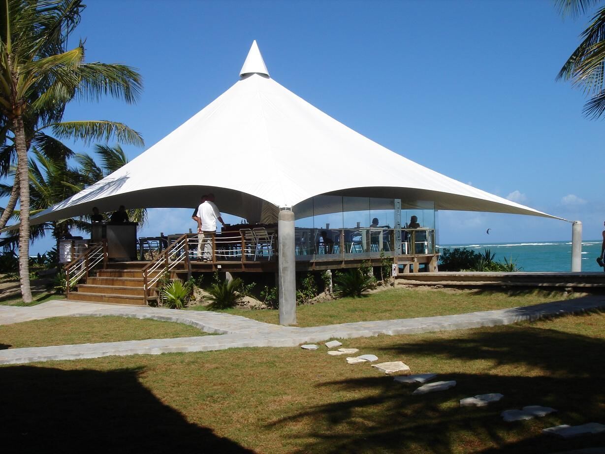 Restaurante de playa bajo cubierta tensada cónica frente al mar